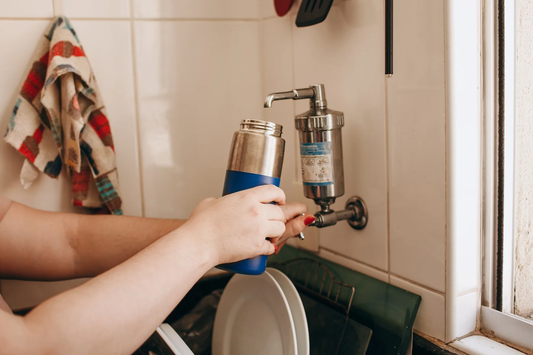 Home faucet filter being used to fill a reusable water bottle