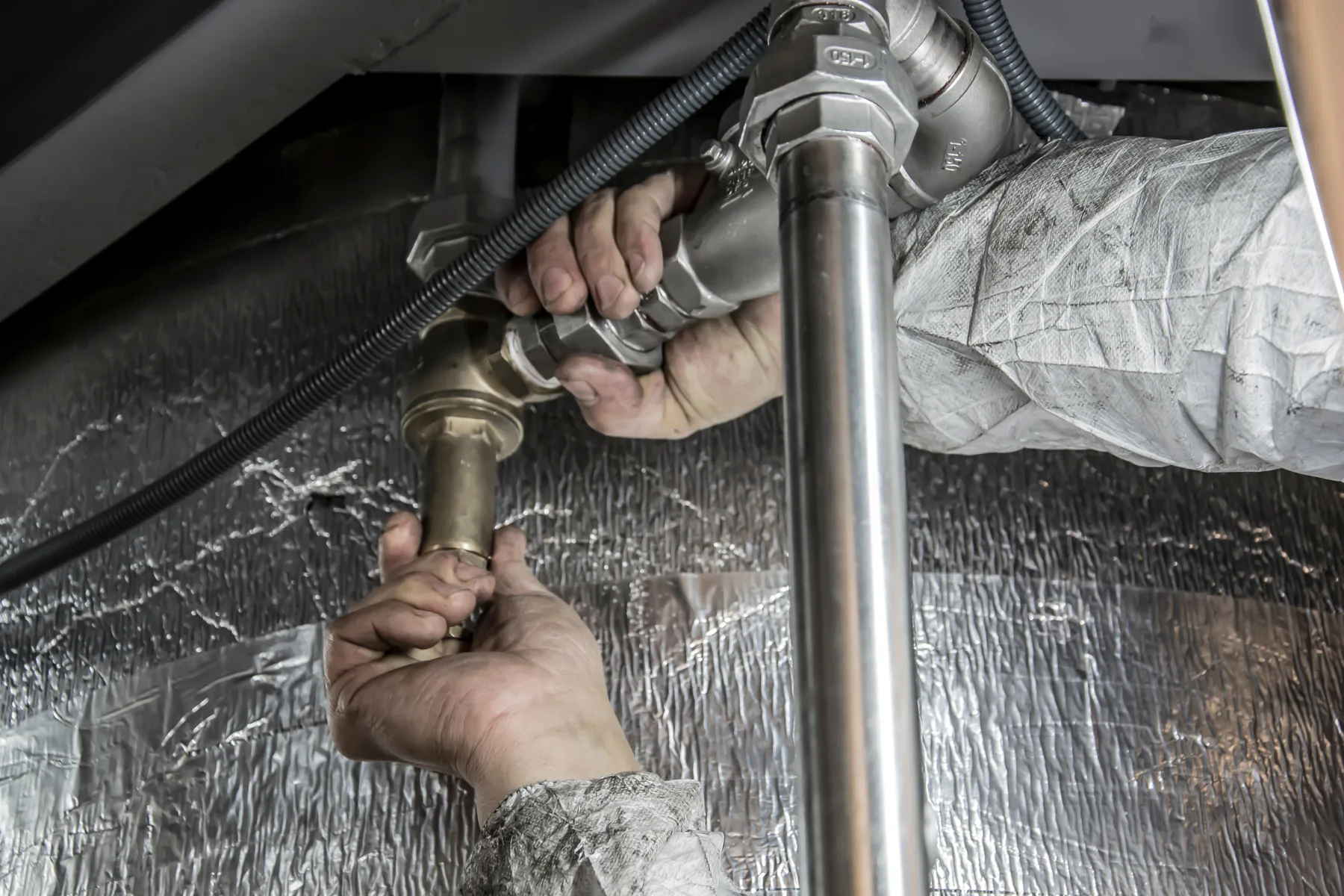 Technician hands working on metal pipe fittings